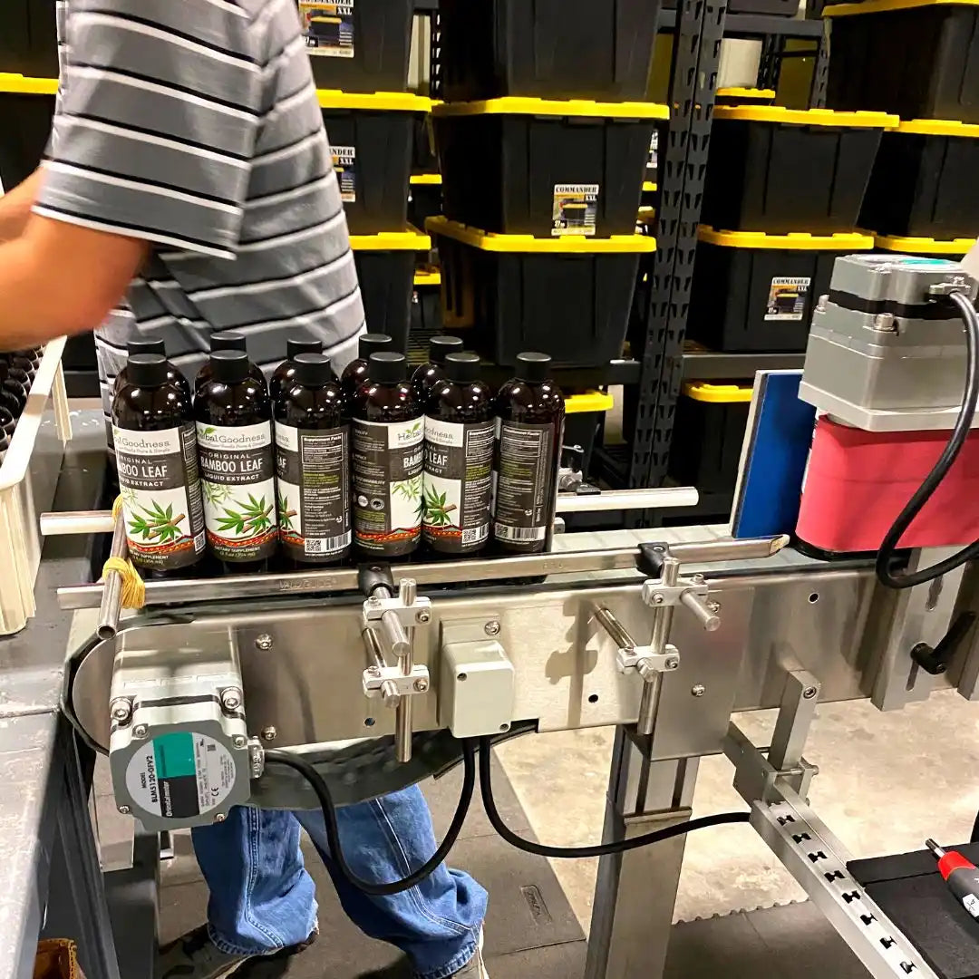 Automated labeling machine applying labels to bottles on a conveyor system.